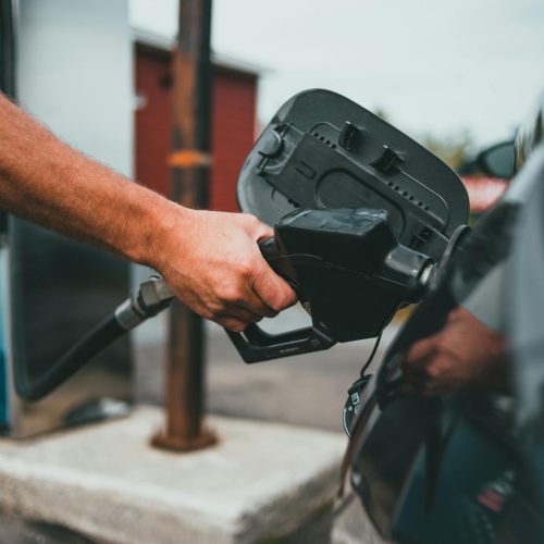 person putting gasoline on a vehicle